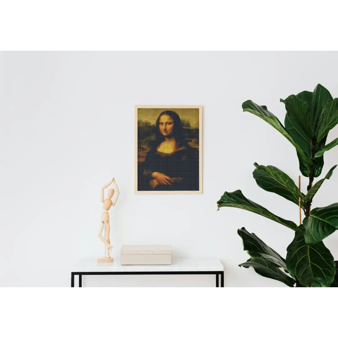 Diamond painting van de Mona Lisa, aan de muur boven een witte tafel met een houten beeld en een groene plant ernaast.