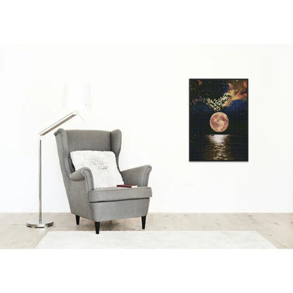 Diamond painting van een volle maan die reflecteert op het water, aan de muur naast een grijze fauteuil en een vloerlamp.